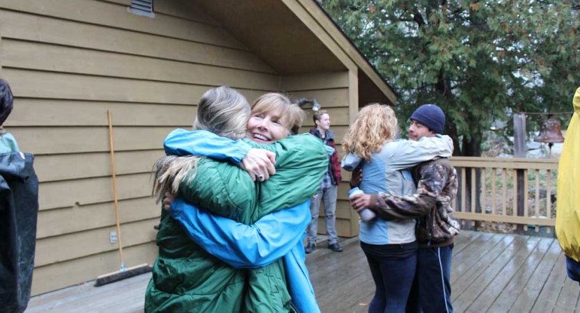 A group of people embrace during the family seminar of an outward bound intercept course.